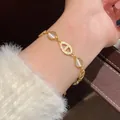 Macro view of gold-tone geometric bracelet with pavé-set stones on wrist - Gold