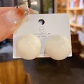 Vista macro dettagliata di orecchini a perno a sfera bianca minimalista con aghi in argento 925. - Orecchino a Sfera / Bianco
