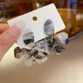 Close-up of elegant resin flower earrings with grey marble ink-wash effect - Tops / Black