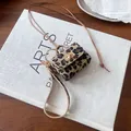 Detailed view of miniature leopard print bag charm with gold clasp and lanyard - Gray