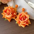 Primer plano de pendientes de rosa de tela naranja con detalles de rafia - Pendientes de Botón (HE30753) / Naranja