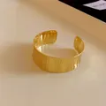Detailed view of golden wide open cuff bracelet featuring elegant vertical textures - Small / Gold