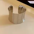 Detailed macro view of a silver-toned metal cuff bracelet with vertical engraved patterns - Large / Silver