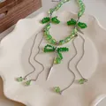 Exquisite green crystal bow necklace with silver cone pendants displayed on a plate - Green