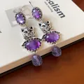 Close-up detail showing the intricate silver cat design and purple stones of these vintage earrings - Silver-Purple
