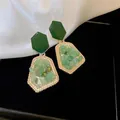Close-up view of green forest-style resin earrings with a geometric gold-textured border - Green