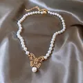 Elegant pearl necklace with a gold-tone butterfly pendant on a soft grey satin surface. - White-Gold Accessories