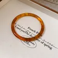 Detailed macro view of a vintage amber-colored bangle featuring elegant wooden grain texture - Dark Amber Translucent Style / Brown
