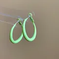Close-up of lime green spray-painted oval hoop earrings on a clear acrylic display stand - 47# Lime Green