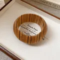 Close-up of a vintage-style bangle featuring a vertical wood grain pattern in a wooden tray. - Vertical Wood Grain Style / Brown