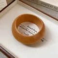 Close-up of a retro wooden bangle with natural grain on a minimalist aesthetic display. - Wide Rounded Closed Style / Light Coffee