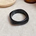 Detail view of black marbled resin square bangle with elegant white swirled patterns - Black