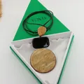 Detail view of geometric resin pendant necklace with marble pattern on a green gift box - Necklace-Black (HN7745) / Ginger Yellow