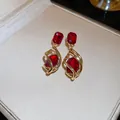 Close-up of vintage red gemstone earrings with gold-toned swirl design and elegant luster. - Style 36#