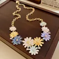 Charming floral enamel necklace with sparkling rhinestones on a wooden jewelry tray - Gold