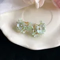 Close-up view of light green floral earrings with sparkling rhinestones and pearls - Green
