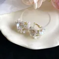 Close-up of elegant flower earrings with white petals and diamond accents on a plate - White