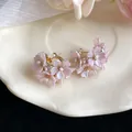 Close-up of pink cherry blossom earrings with sparkling crystals and pearls on a white plate - Pink