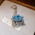 Detail view of a cute acrylic cat keychain wearing a shark hat with funny meme design - Shark Costume Biting Cat / Silver