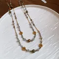 Bohemian ethnic style beaded necklace with gold flower charms on white ceramic plate - Style 18 Necklace / Gold and Floral