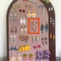 Detailed view of forest style floral tassel dangle earrings on a beige display board - Size 11