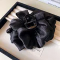 Macro view of a elegant black ruffled fabric hair claw clip for thick hair styling - Black