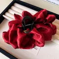 Detail view of a large pleated dark red fabric hair claw clip placed in a jewelry box - Red