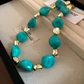 Close-up of irregular turquoise and gold beaded necklace in a jewelry display box - Necklace / Green