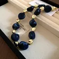 Macro detail of irregular blue marbled beads and gold metallic necklace in a box - Necklace / Blue