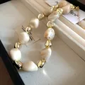 Close-up detail showing the irregular dyed beads and gold accents of a retro fashion necklace - Necklace / White