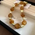 Detail of vintage style necklace with irregular marbled amber beads and gold accents - Necklace / Brown