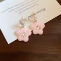 Close-up of elegant pink flower earrings with clear crystal accents on wooden background - 42# Enamel Five-Petal Rhinestone Studs (HE25000)