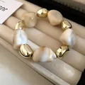 Detailed view of irregular marbled and golden beads of a vintage style necklace. - Bracelet / White
