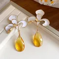 Macro view of white enamel flower drop earrings with amber translucent teardrop pendants - Gold White Yellow (Silver Post)