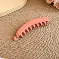 Gros plan d'une pince à cheveux banane rose mat montrant ses dents et sa texture lisse. - Pinces à ressort / Orange