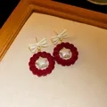 Close-up detail of red velvet bow earrings with a pearlescent star in a wooden frame - Bowknot Wreath Style (HE16757) / Red (Silver Post)