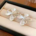 Primer plano detallado que muestra el acabado mate de los pendientes de flores plateados - Plateado