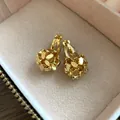 Close-up detail of 18k gold plated floral cluster clip-on earrings in a beige jewelry box - Flower Cluster / Gold