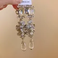 Close-up of ornate silver dangle earrings with crystals and clear teardrop pendants - Long Flower Water Drop Style (HE21548) / Silver