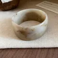 Detailed view of a wide resin bangle with a brown marble-patterned finish on canvas - Off White