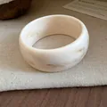 Close-up of a marbled off-white resin bangle bracelet on a linen surface - White