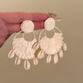 Detaillierte Makroansicht von Bohème-Raffia-Ohrringen mit echten Muschel-Hängern - Fan Shaped Shell Ornament Style / Weiß