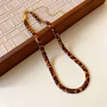 Macro detail view of a retro leopard print snake bone chain necklace with gold finish - Gold Brown