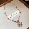 Vue détaillée du collier pendentif étoile fait main avec cordon marron et perles - Blanc-Café