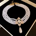 Multi-strand pearl choker with vintage gold crystal pendant and drop pearl detail. - White