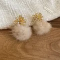 Macro detail of elegant golden flower stud earrings featuring soft beige faux fur pom-poms - Silver Earring Post Style / Brown