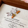 Primo piano dettagliato di orecchini a forma di coniglio con carota su cartoncino - Stile Coniglio Carota Arancione