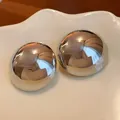 Close-up of chunky silver-toned dome stud earrings with reflective mirror finish - Glossy / Silver