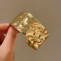 Vista dettagliata di un ampio bracciale a polsino dorato martellato irregolare di lusso - Cuff Bracelet / Oro