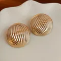 Macro view of golden semi-circular dome stud earrings with vertical striped texture - Striped / Gold